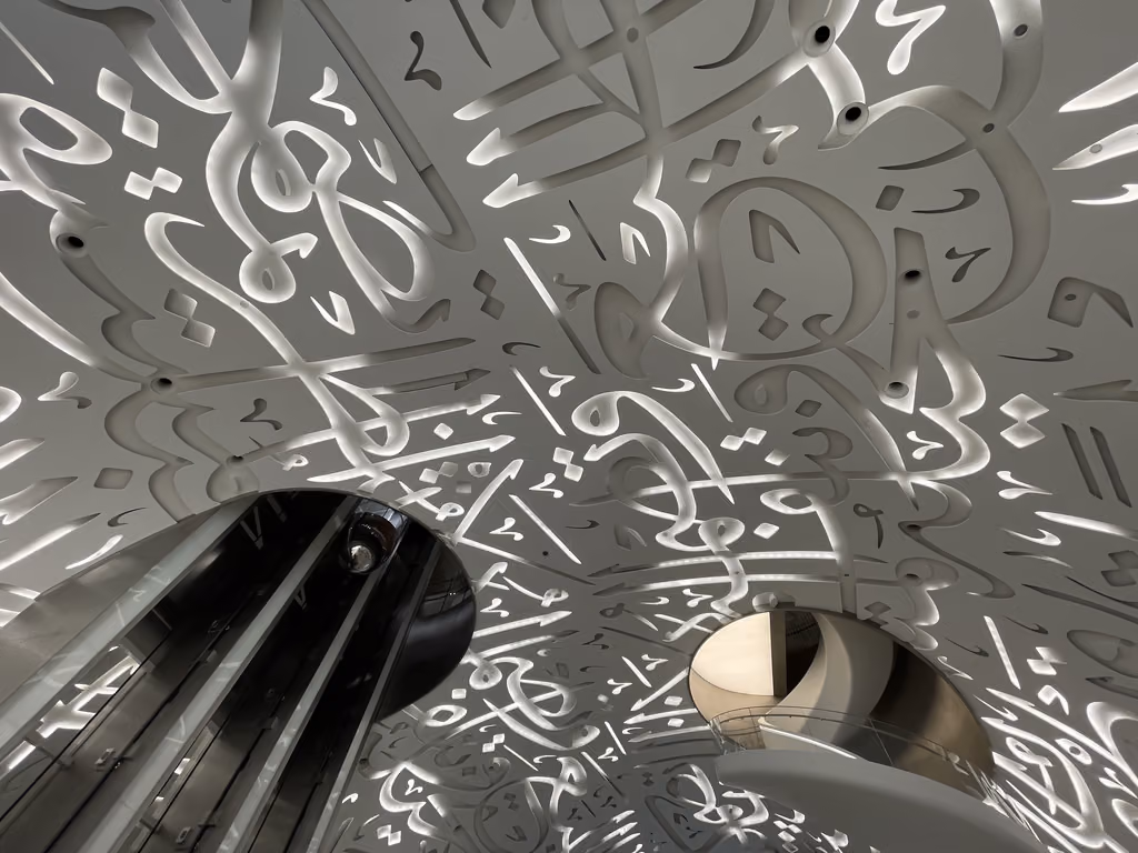 Intricate Arabic calligraphy patterns illuminated on the curved white interior walls of the Museum of the Future in Dubai.