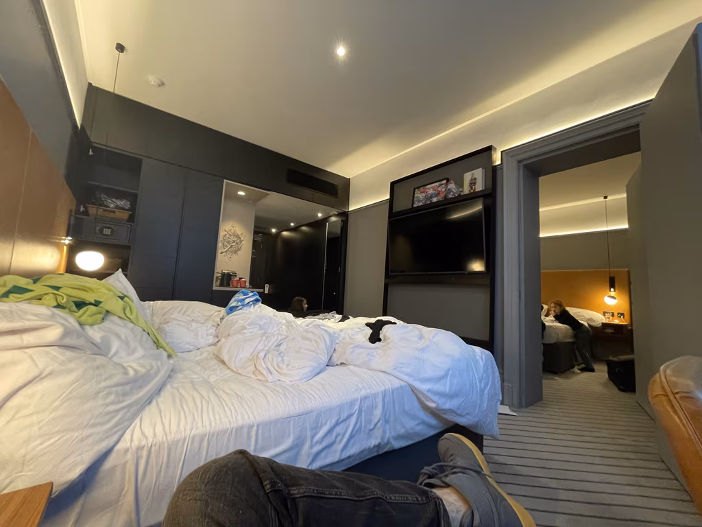 Interior view of two connecting hotel rooms at Andaz London Liverpool Street with two beds and people inside.