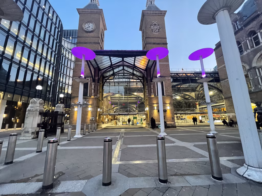 The historic brick entrance of the Andaz London Liverpool Street hotel with modern illuminated purple light fixtures.