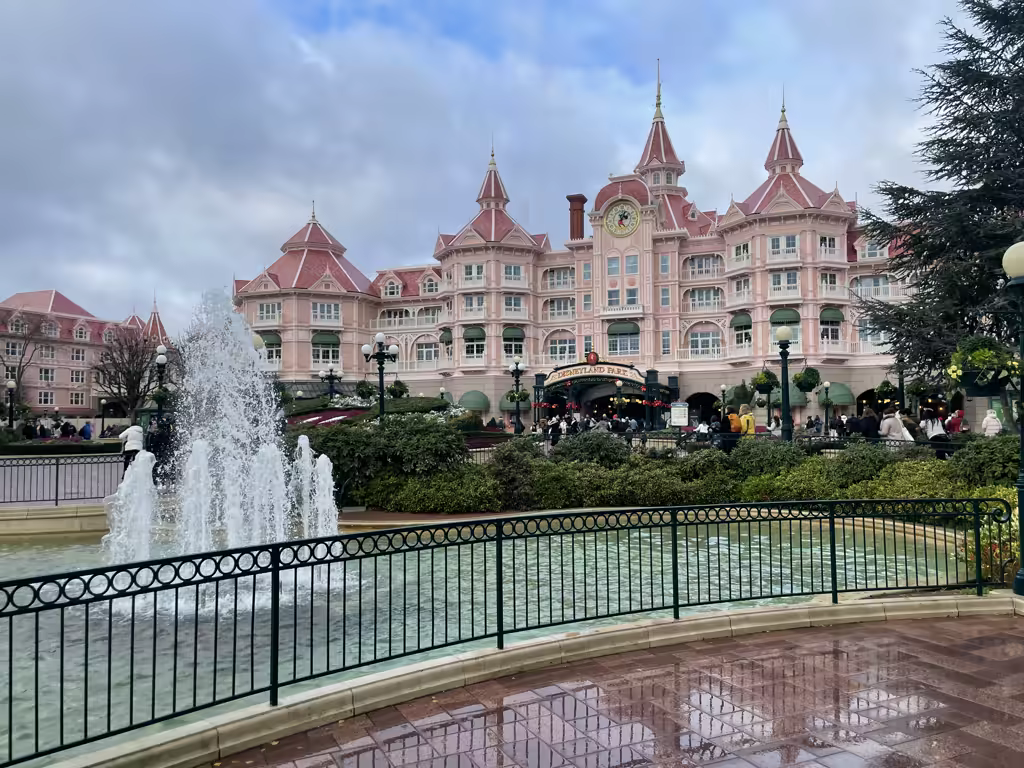 A wide shot of the Disneyland Hotel in Disneyland Paris with a fountain in the foreground.
