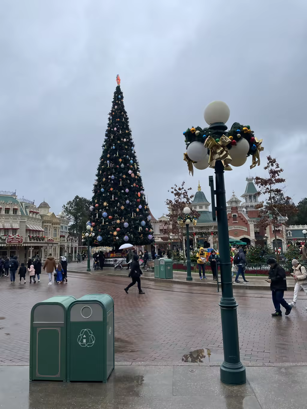 A large decorated Christmas tree in Town Square at Disneyland Paris on a cloudy day.