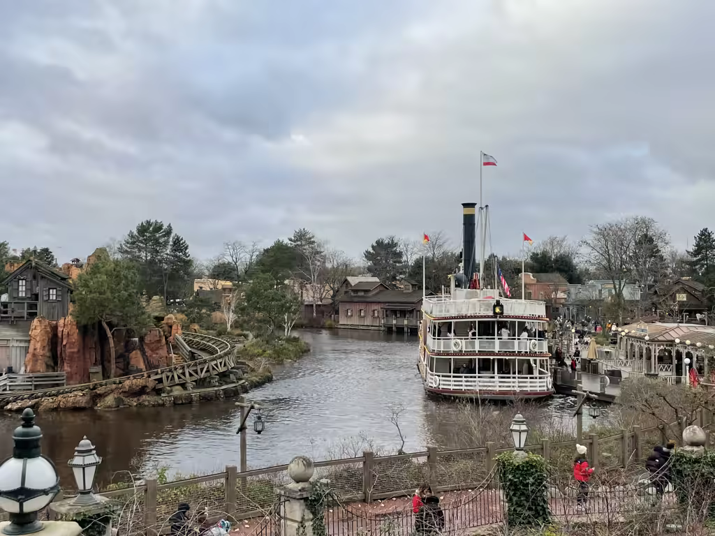 Experience the charm of Frontierland as the Mark Twain riverboat glides peacefully past Big Thunder Mountain.