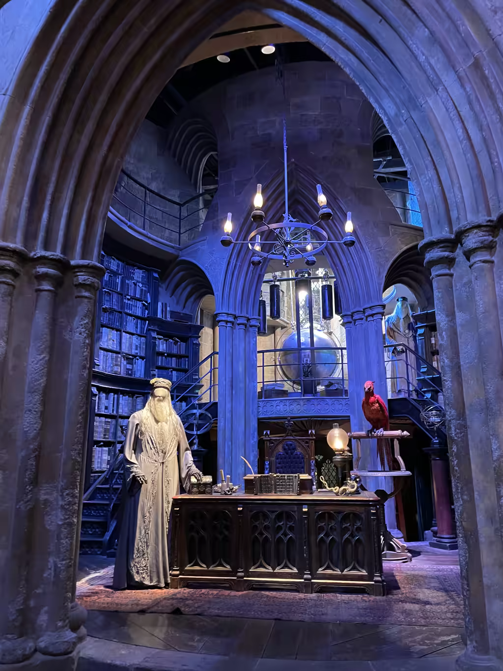 Dumbledore's office set at the Warner Bros. Studio Tour London featuring a desk and Fawkes the phoenix.