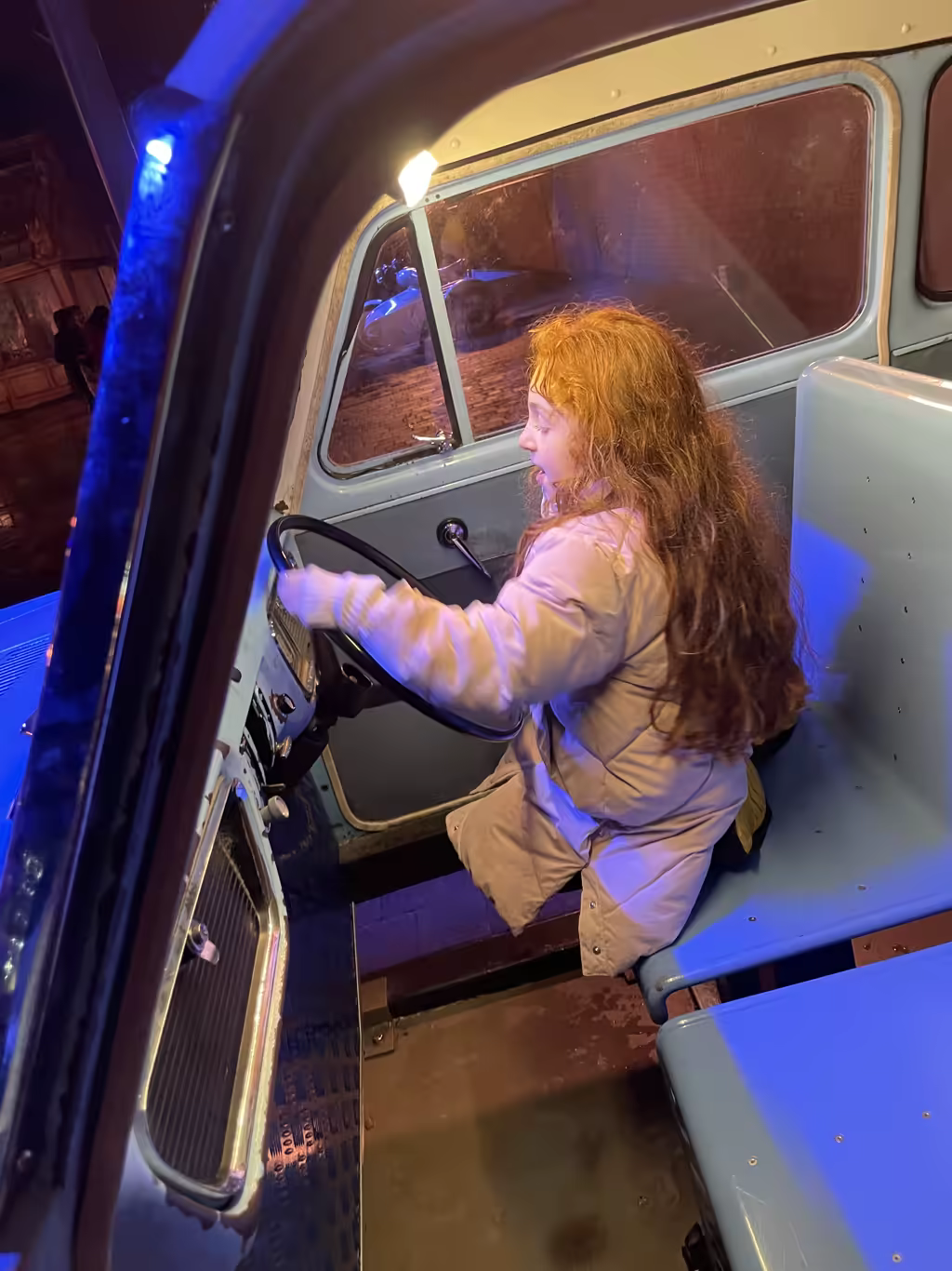 Child sitting in the driver's seat of the Knight Bus at the Harry Potter Studio Tour London.
