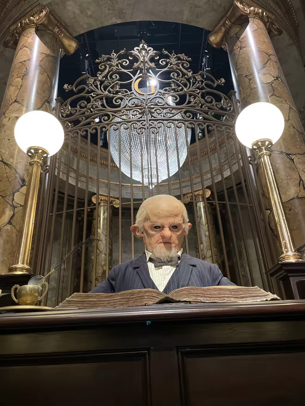 Gringotts goblin banker sitting at a desk behind iron gates at Warner Bros. Studio Tour London.