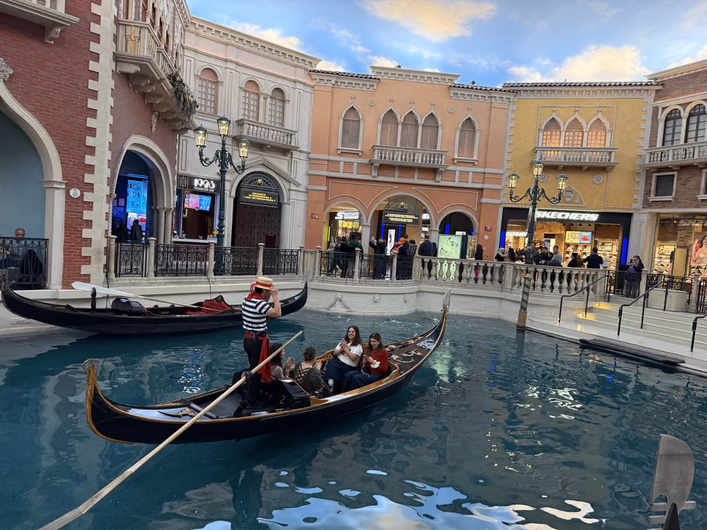 Gondolier rowing a boat with tourists along the indoor canal at The Venetian Las Vegas resort.