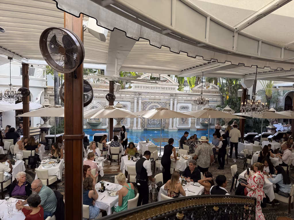 Guests dining outdoors on the patio at The Villa Casa Casuarina by the ornate swimming pool in Miami.