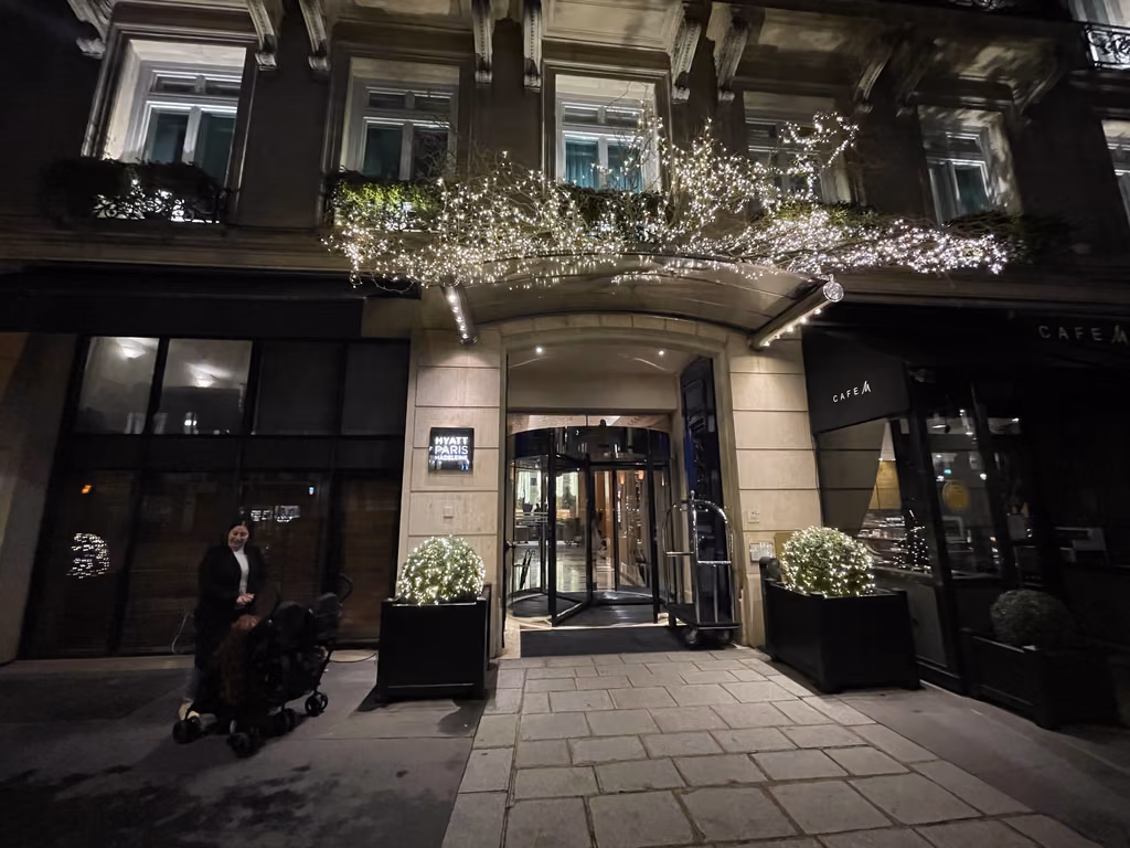 A woman with a stroller arriving at the Hyatt Paris Madeleine hotel entrance at night in Paris.