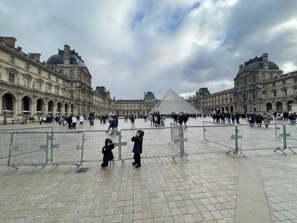 Bundled up in their winter coats, our little explorers marvel at the iconic Louvre Pyramid.