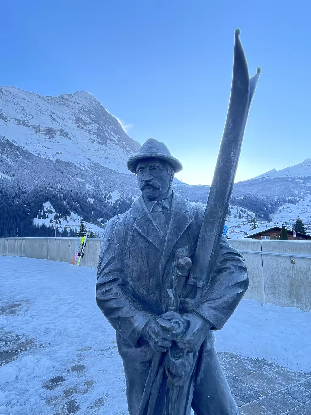 A bronze statue of a historic skier stands proudly against the breathtaking backdrop of the Eiger.