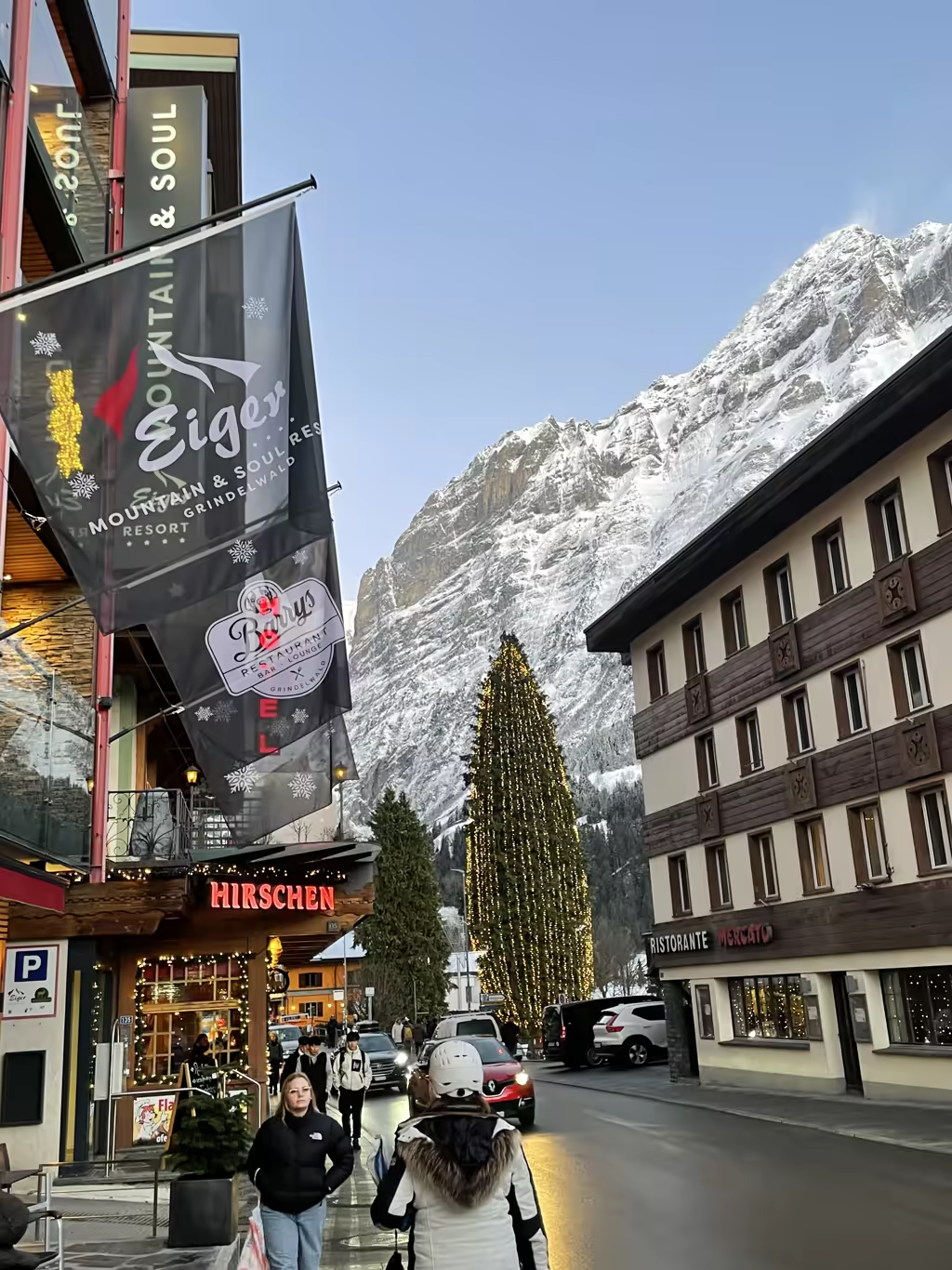 The festive atmosphere of Grindelwald shines bright beneath the towering, snow-dusted peak of the iconic Eiger.