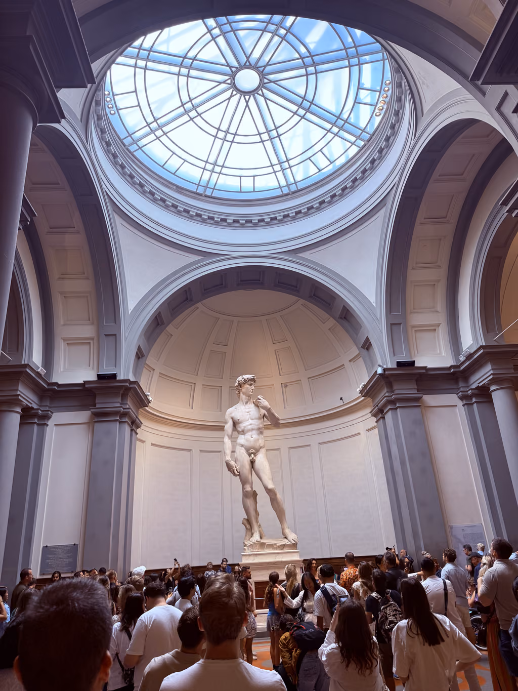 Tourists viewing Michelangelo's David statue under the dome of the Accademia Gallery in Florence.
