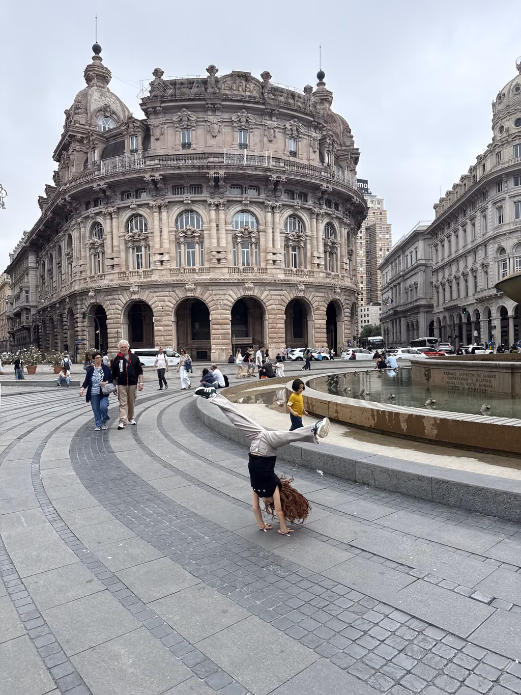 Girl doing a handstand in front of the Palazzo della Borsa in Genoa, Italy.