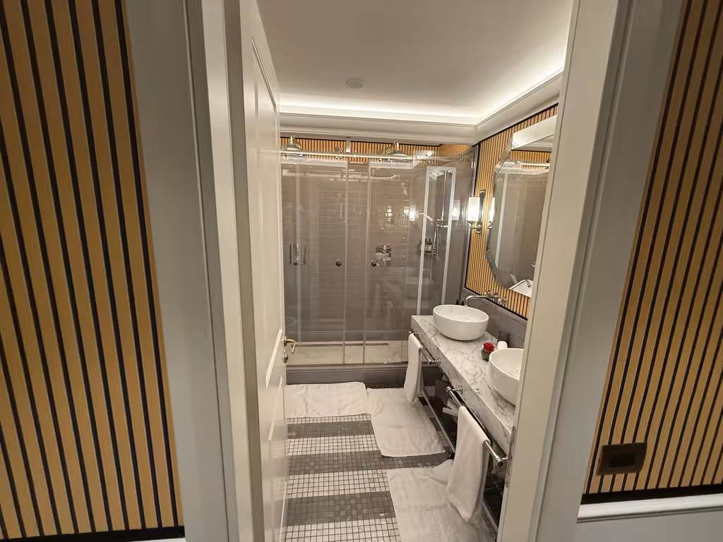 The stylish marble-clad bathroom at Il Tornabuoni features dual vessel sinks and an expansive walk-in shower.