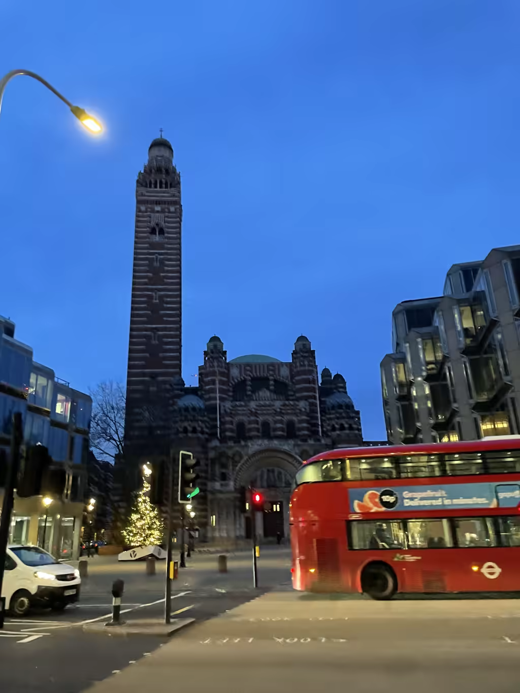 Iconic Westminster Cathedral sets a festive holiday scene as a red London bus passes by at twilight.