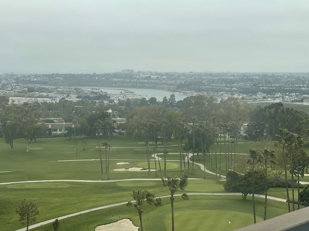 Elevated view from the VEA Newport Beach resort balcony overlooking the lush golf course and Newport Bay.
