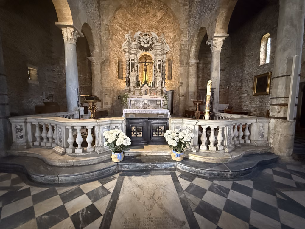 Ornate altar with marble balustrade inside a historic church in Pisa, Italy.