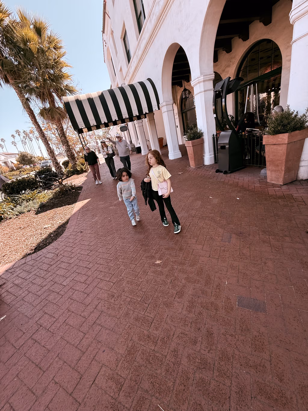 The kids explore the elegant outdoor plaza and iconic striped awnings at this Santa Barbara resort.