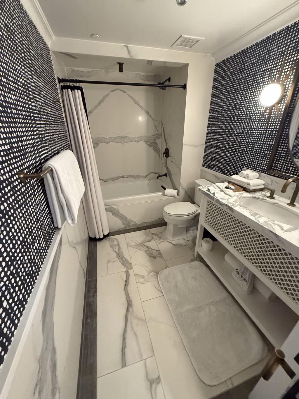 The stylishly renovated bathroom at our Santa Barbara hotel blends modern marble finishes with chic wallpaper.