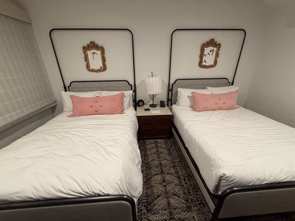 Twin beds with stylish iron frames and chic pink accents create a cozy Santa Barbara retreat.