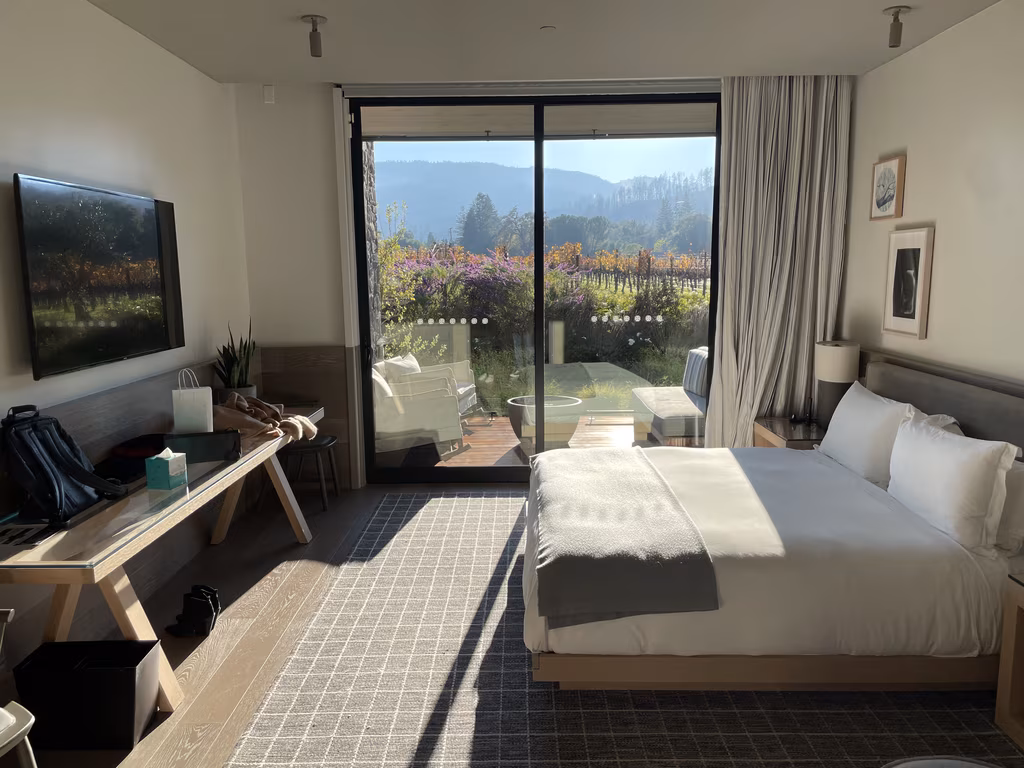 Modern bedroom at Alila Napa Valley with a vineyard view through floor-to-ceiling glass doors.