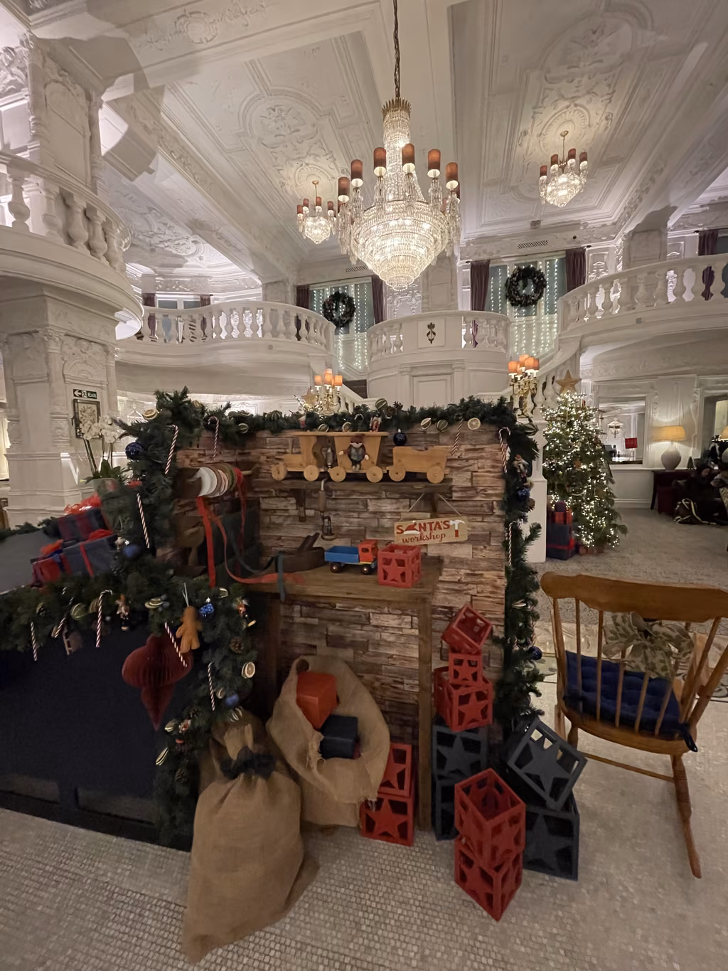 A festive Santa's workshop display featuring wooden toys and gift-filled sacks in the grand lobby of St. Ermin's Hotel in London.