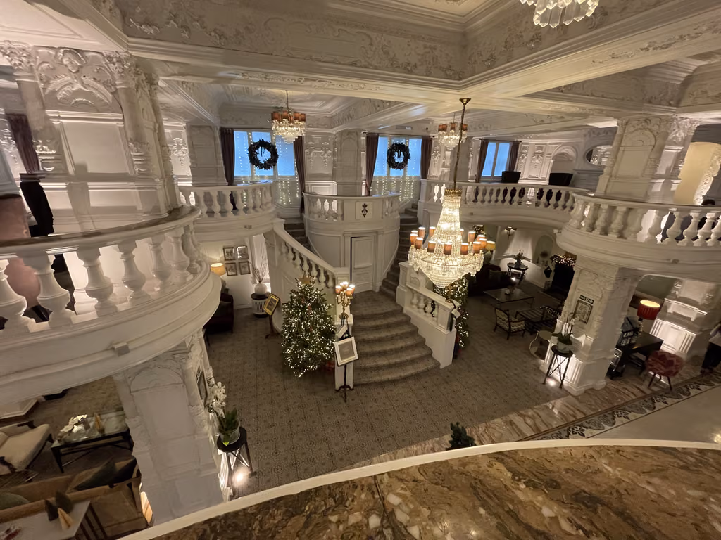 Ornate, white architectural staircase in the grand lobby of St. Ermin's Hotel in London decorated for Christmas.
