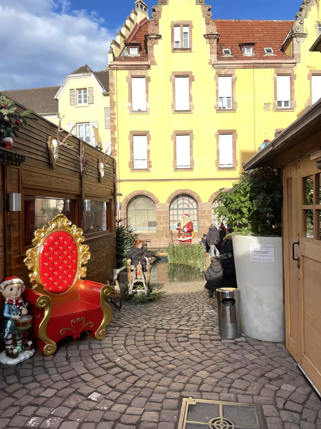 A charming, cobblestoned corner in Colmar featuring a decorative Santa throne and festive holiday cheer.