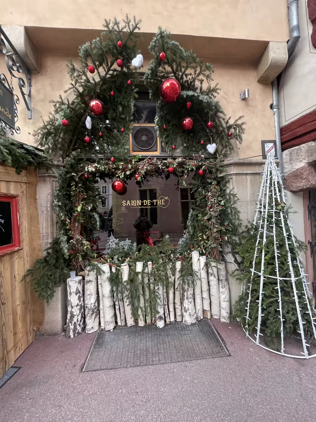 Charming storefronts in Colmar create a festive, woodland-inspired entrance for local tea rooms during Christmas.