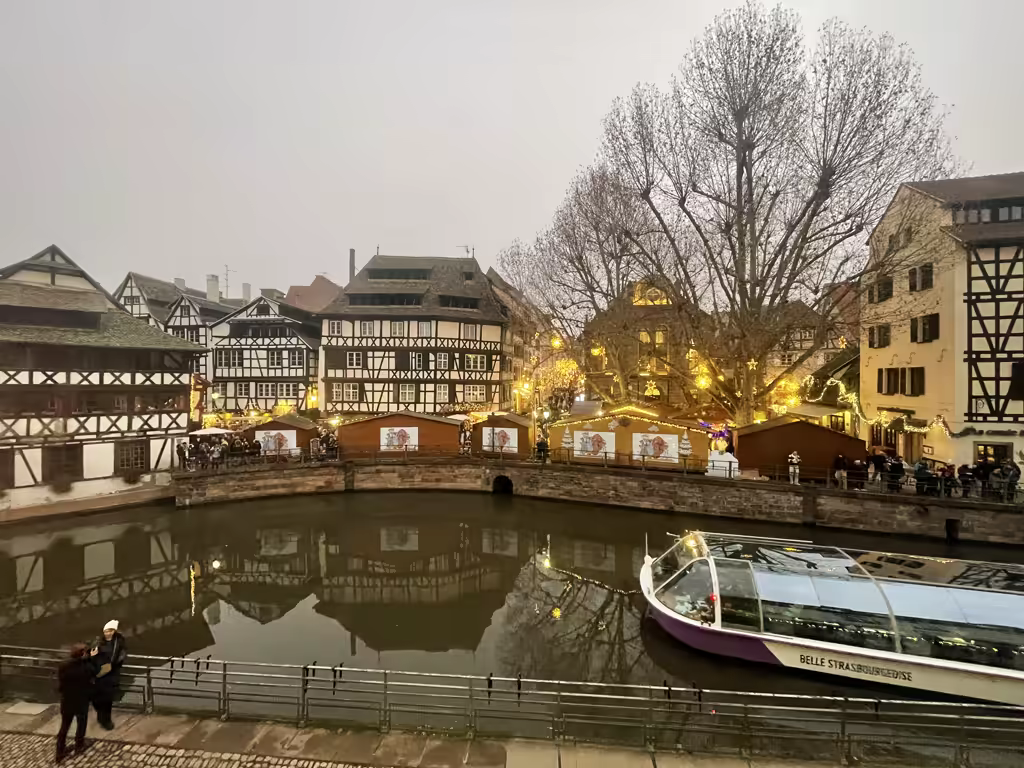 Half-timbered houses and market stalls along the Petite France canal in Strasbourg at twilight.