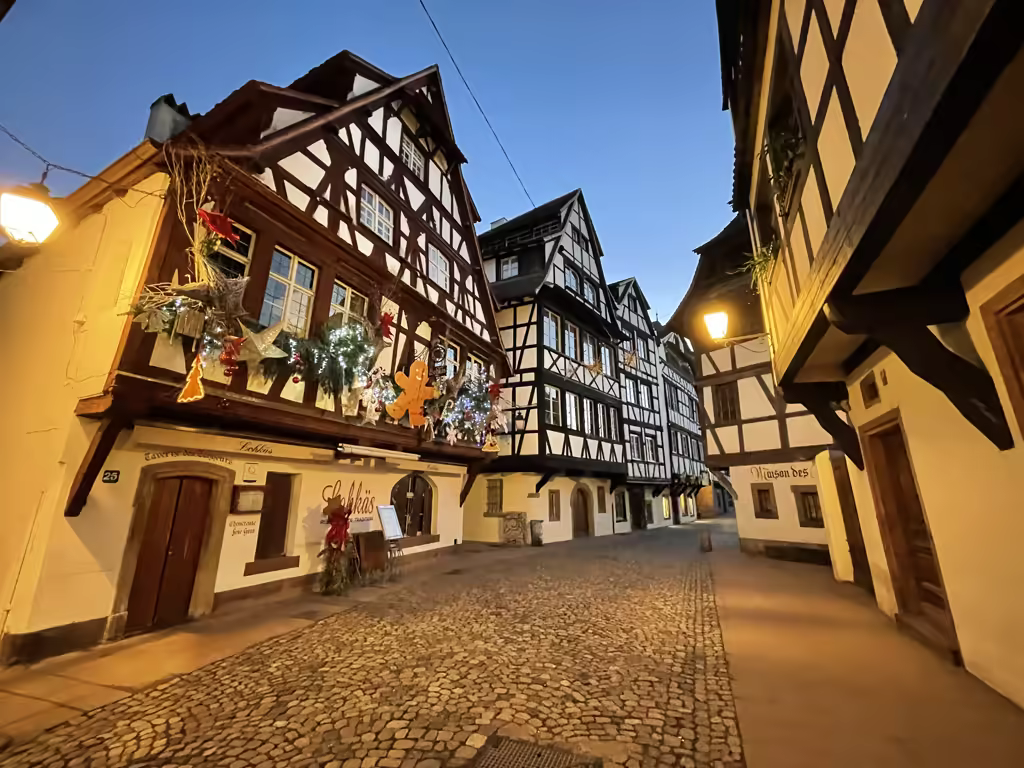 Cobbled streets in Strasbourg glow under warm evening lights during the enchanting Christmas market season.
