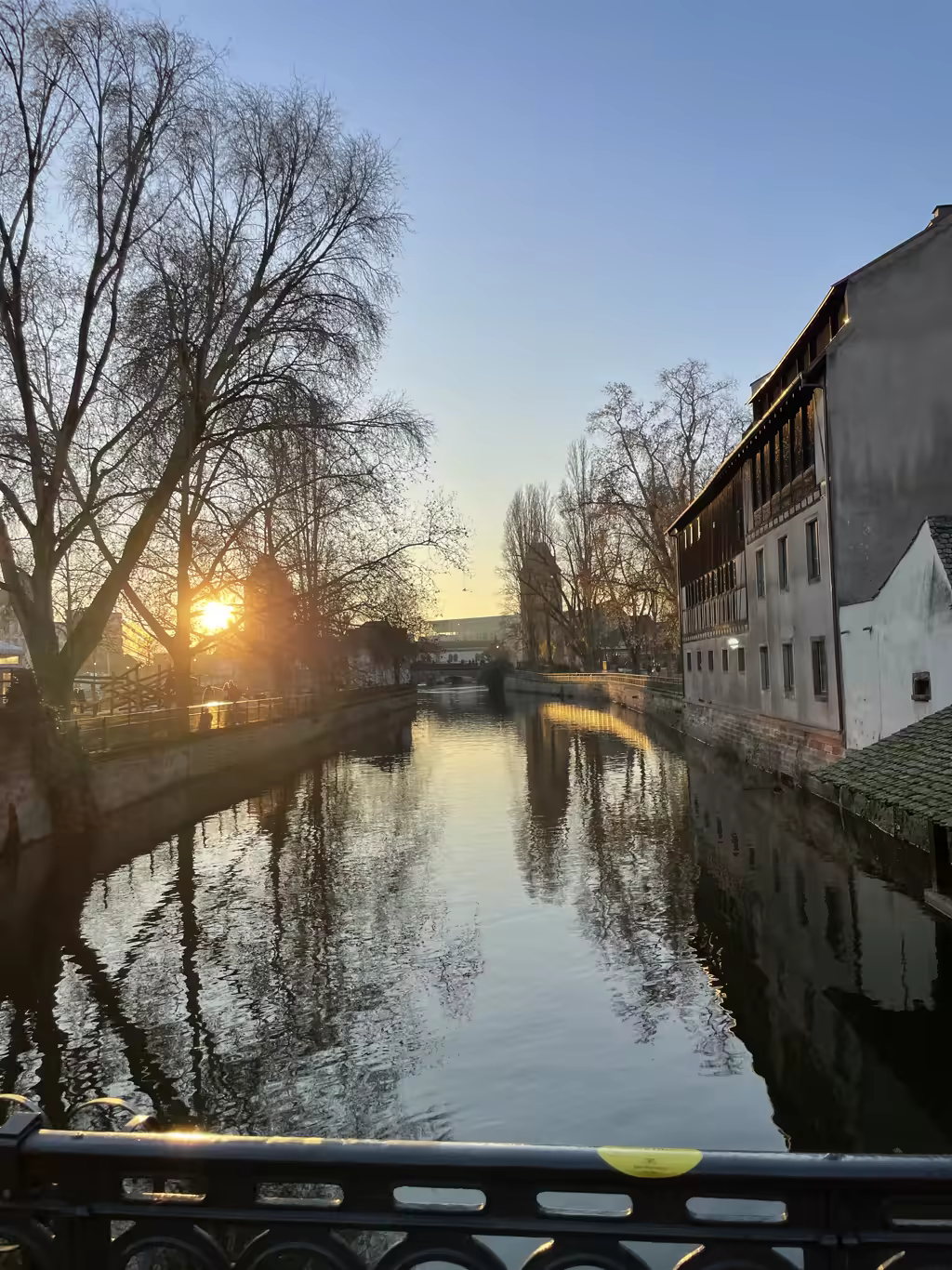 Watching the golden hour light reflect off the quiet canals of Strasbourg during a winter sunset.