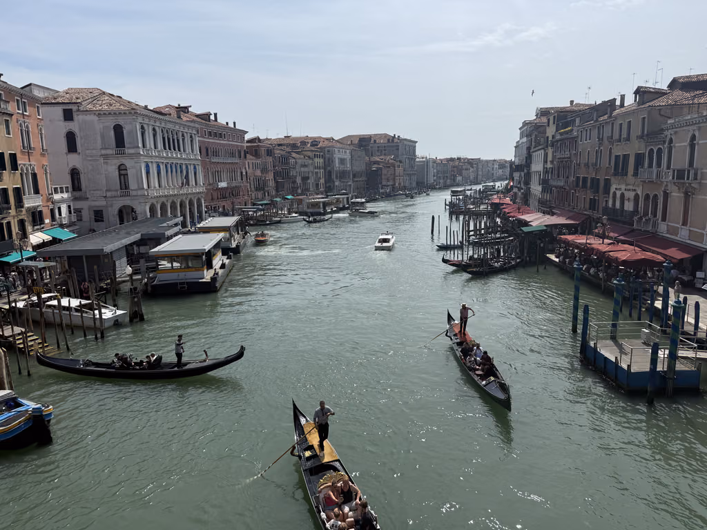 Gondolas and boats traveling along the Grand Canal in Venice, Italy, on a sunny day.