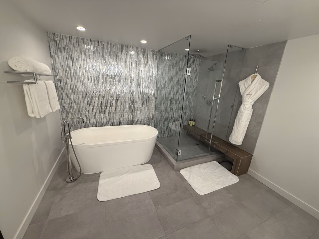 Unwind in the sleek, spacious bathroom featuring a deep soaking tub and an expansive rainfall shower.
